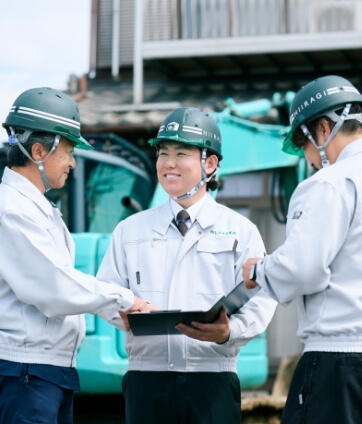 解体現場で笑顔で会話をする3人